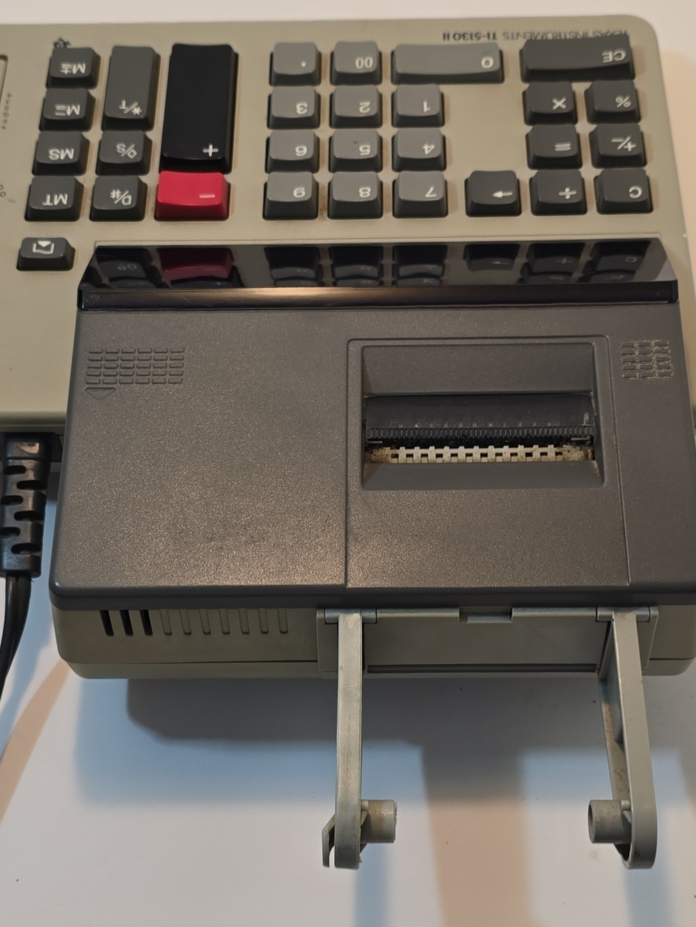 Texas Instruments gray calculator with red accent key and built-in printer